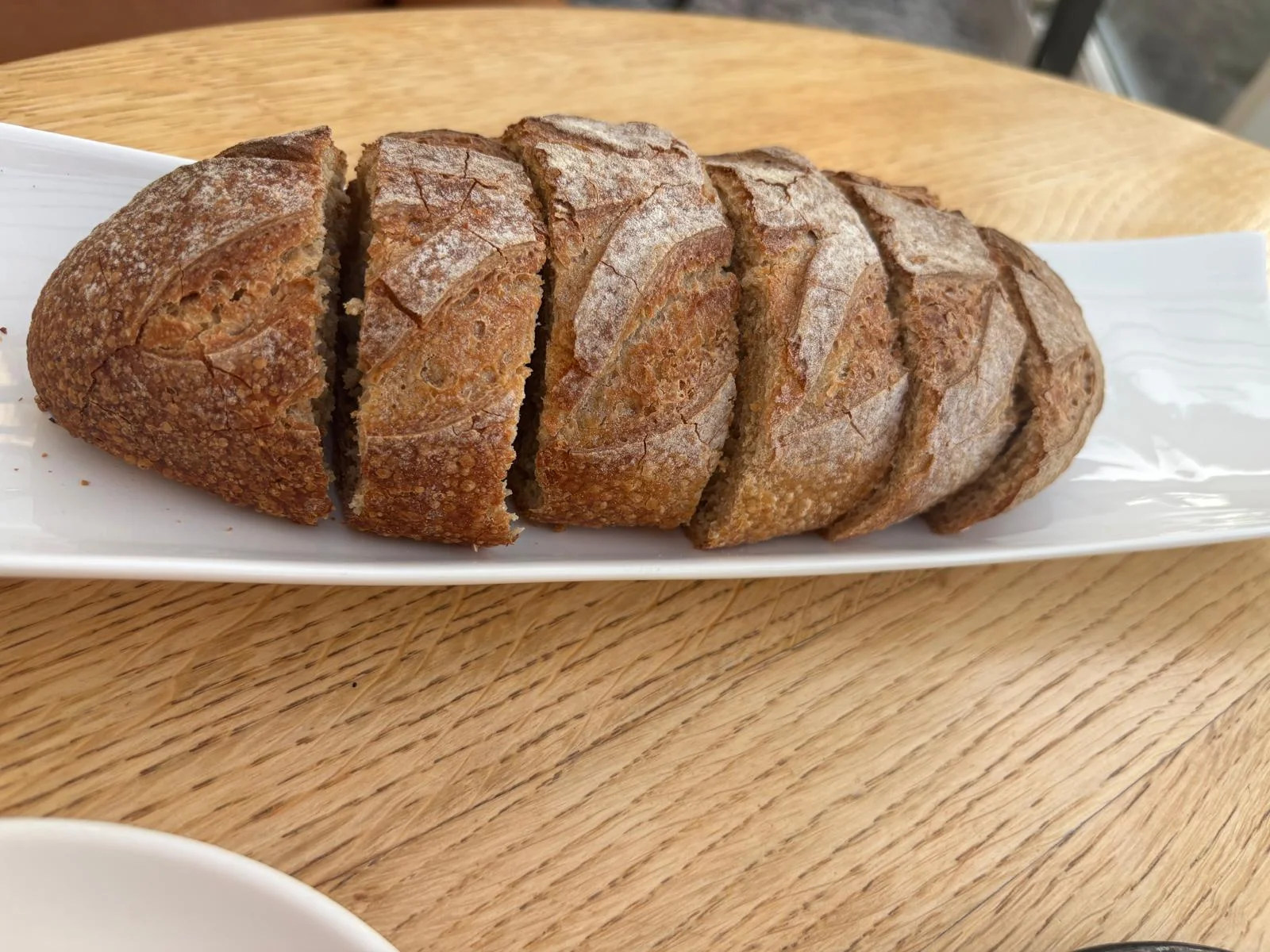 Sliced Breton sourdough served on a white rectangular plate, the bread that traditionally accompanies Beurre de Madame at the table