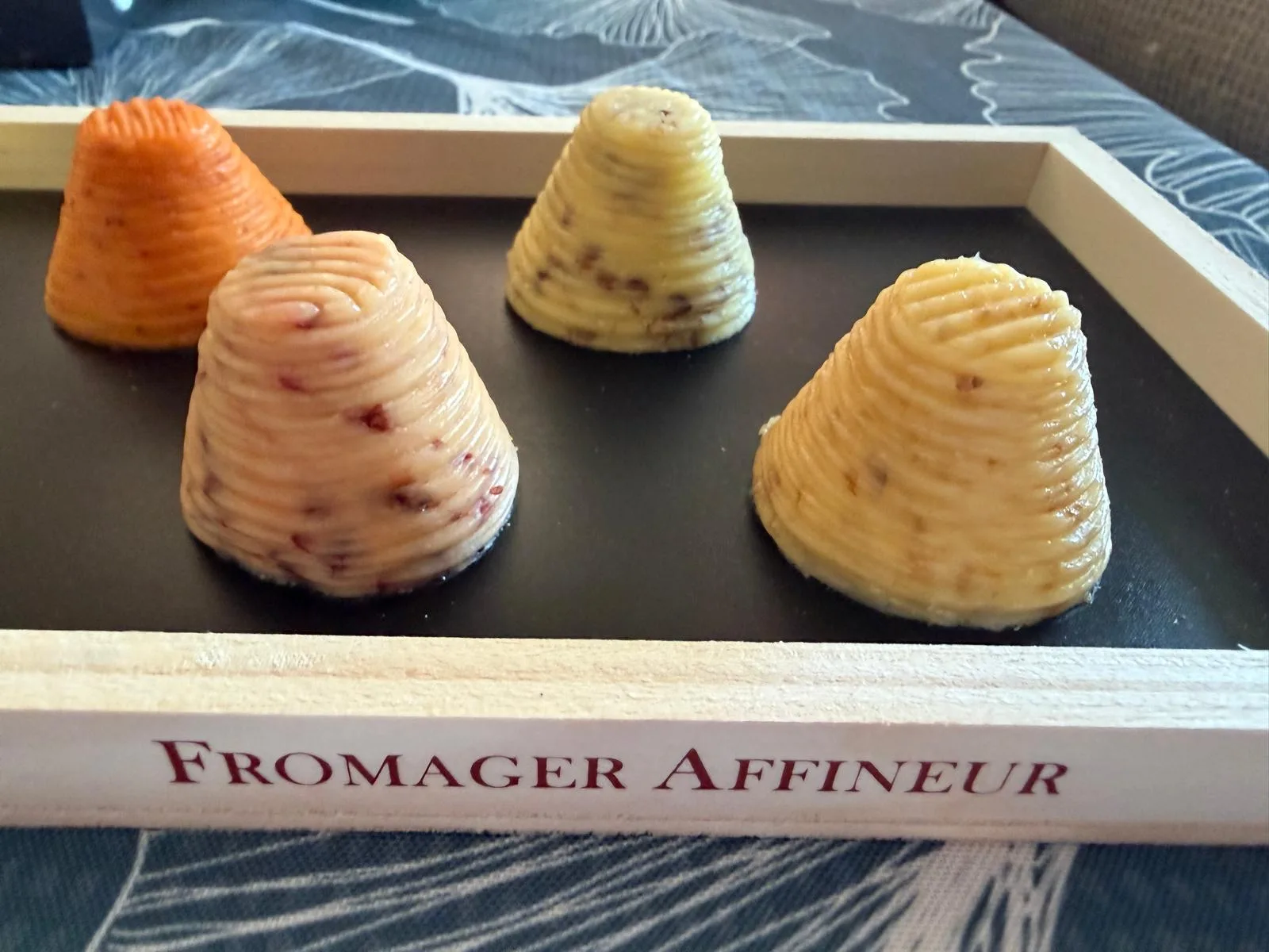 Bordier flavored butters shaped into ridged cones on a Maison Bordier wooden tray, in shades of green, yellow, orange and pink