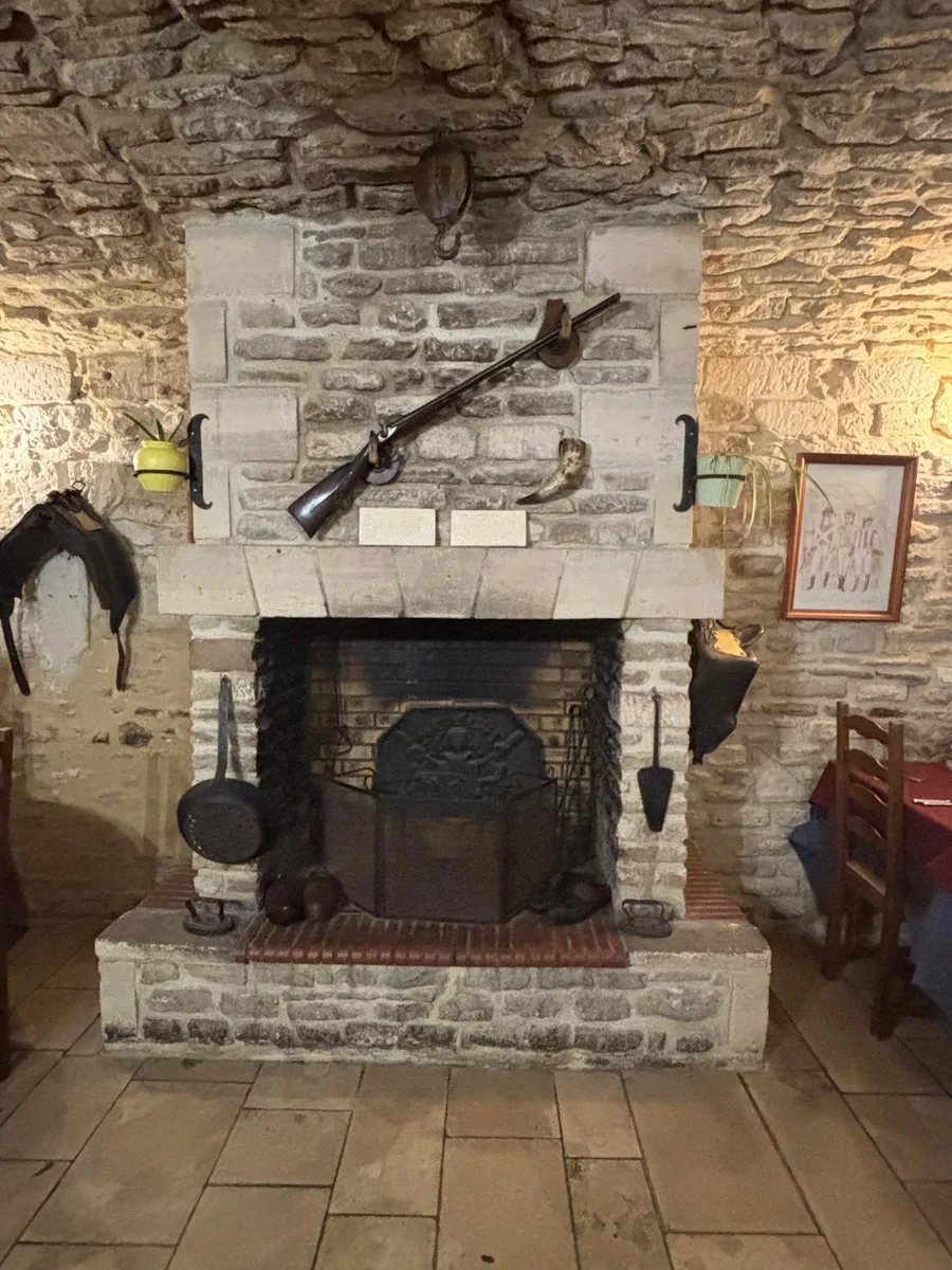 A large stone fireplace with an antique rifle and powder horn above the mantel