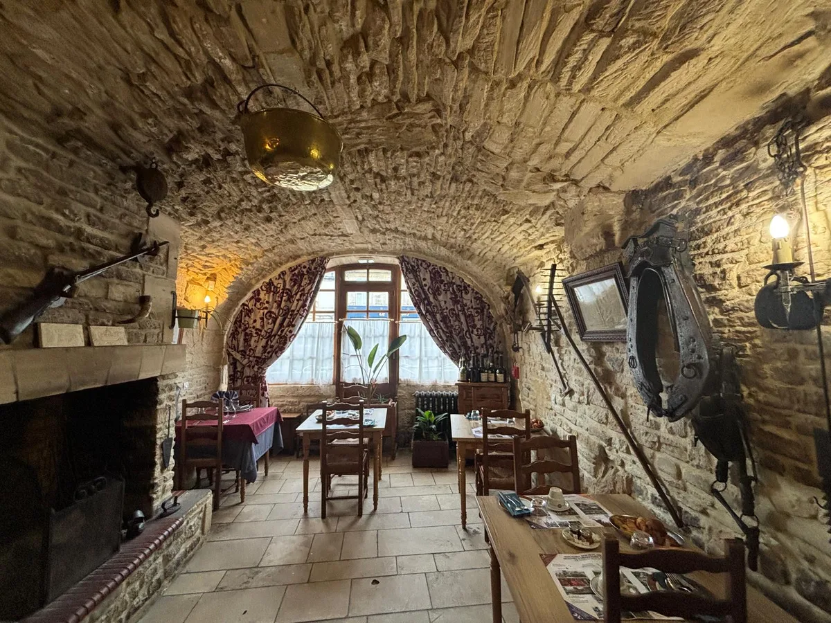 A vaulted stone dining room with hanging copper cauldron and horse collar