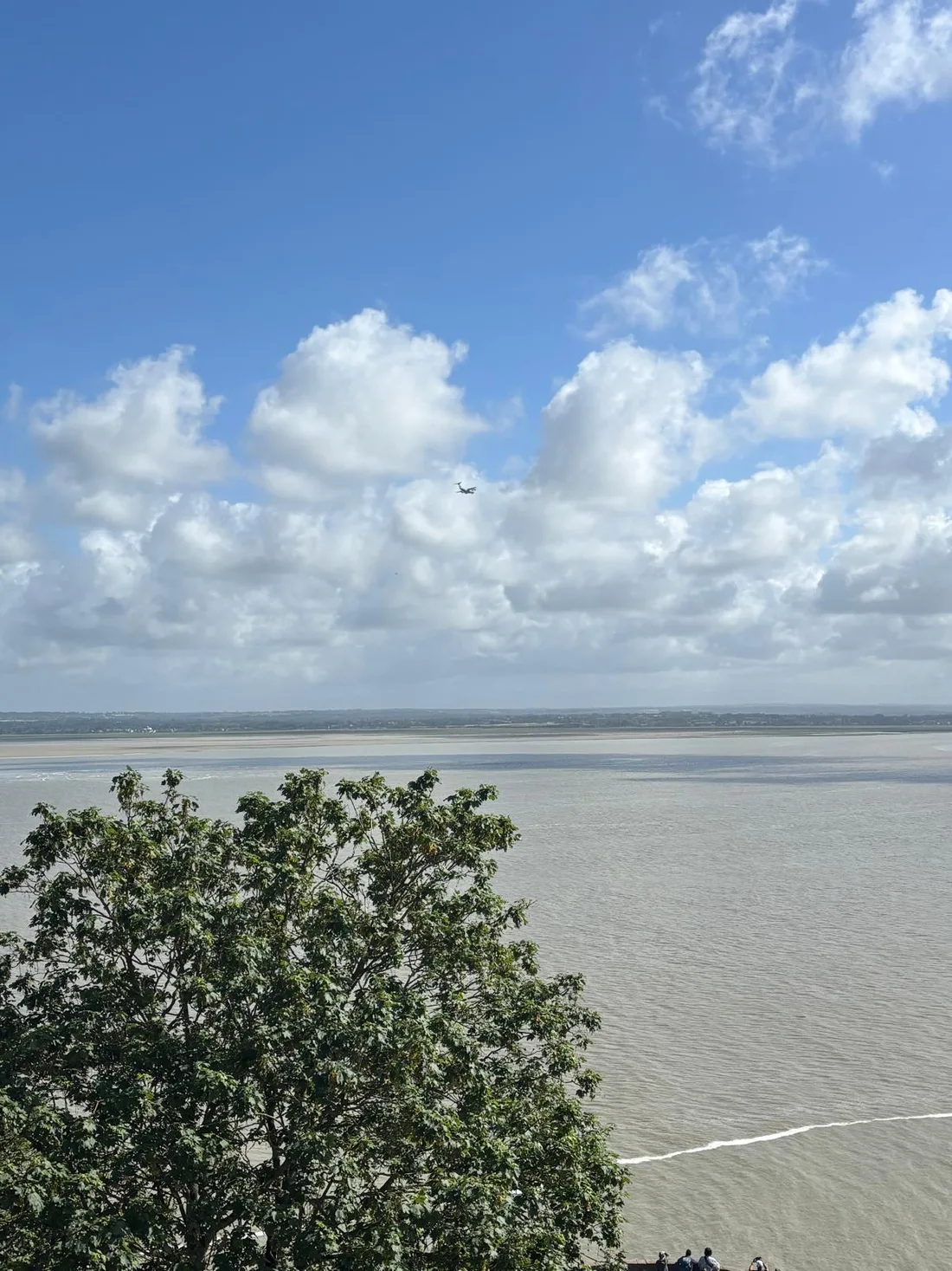 A military aircraft crossing the sky over the bay of Mont-Saint-Michel