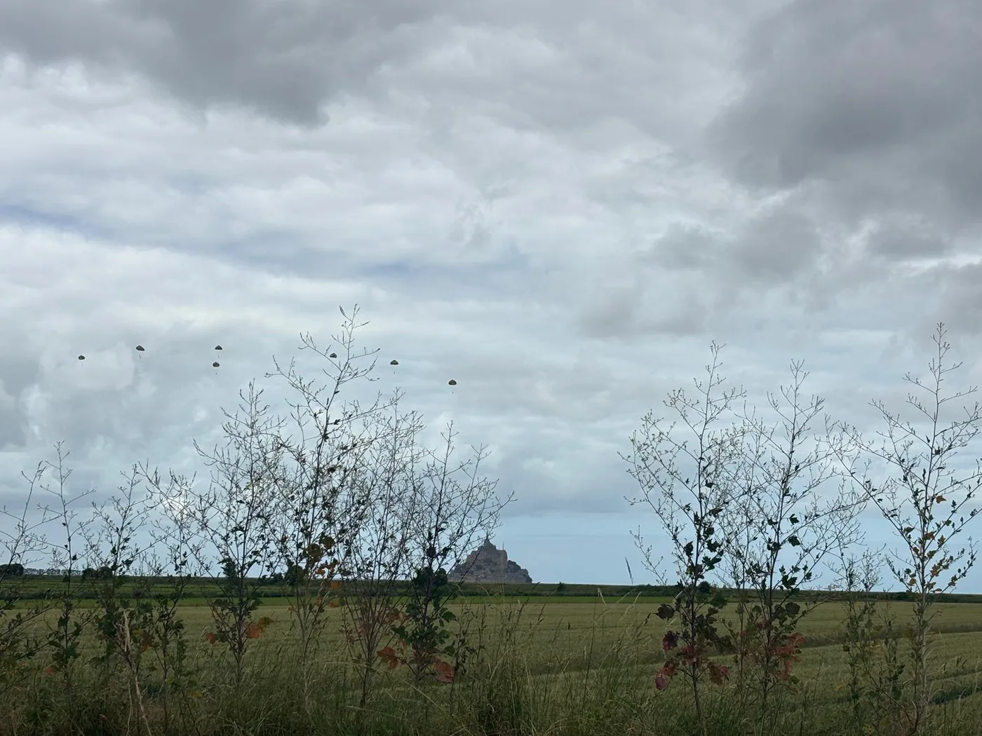 Parachutes in the sky above the bay with Mont-Saint-Michel in the distance
